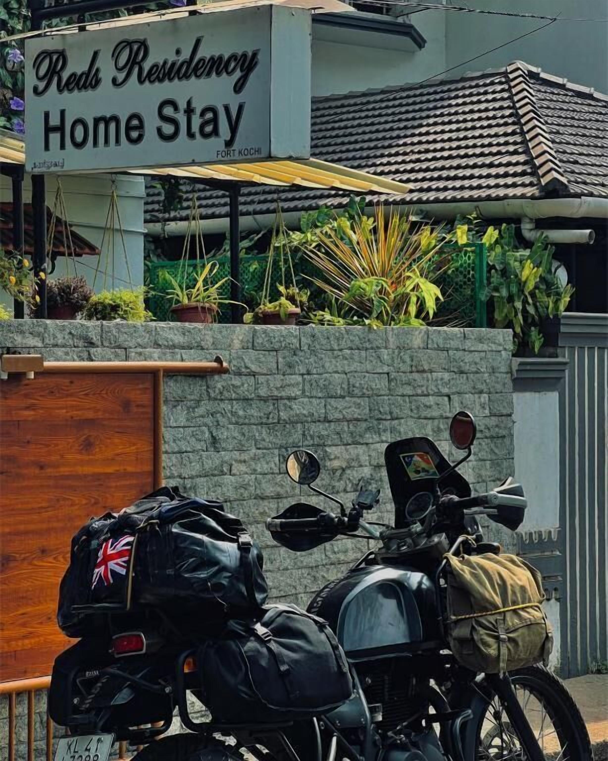 Une moto était garée devant un immeuble sur lequel on pouvait lire une enseigne indiquant « Reds Residency Home Stay ».