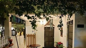 Un patio exterior acogedor con suelo de baldosas, una mesa de madera y sillas.
