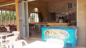 A restaurant with outdoor seating, a bar, and a colorful ice cream display. - Summerdays Studios (Rhodes)