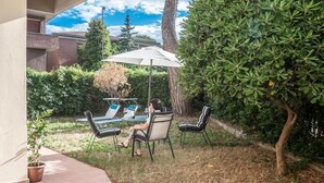 Un patio al aire libre con una mesa, sillas, un paraguas grande y una planta en maceta.