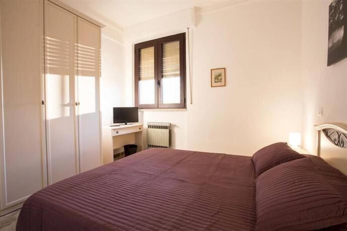 Ein Schlafzimmer mit Bett, Schreibtisch, Stuhl, Heizkörper und Kleiderschrank.