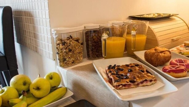 Un bufé de desayuno con frutas, cereales, jugos, pastelería y pan.