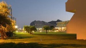 A hotel with a grassy courtyard, trees, and a mountain in the background. - Relax Hotel (Phnom Penh)