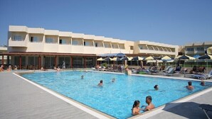 A swimming pool area with multiple people swimming and lounging. There are umbrellas and lounge chairs around the pool. - Relax Hotel (Phnom Penh)