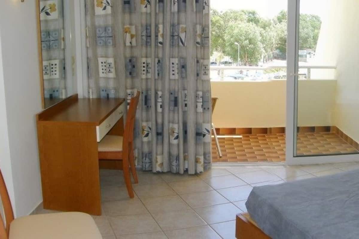 A hotel room with a bed, a desk, and a balcony.