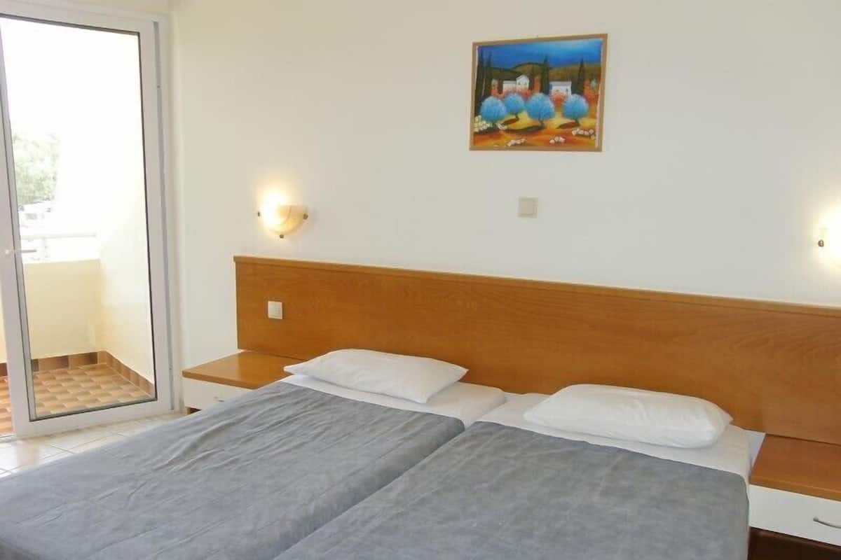 A double bed with a wooden headboard, two bedside tables, and a painting on the wall.