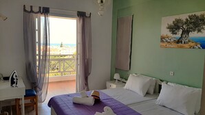 Habitación de hotel con cama, escritorio, silla, un cuadro y vista al mar.