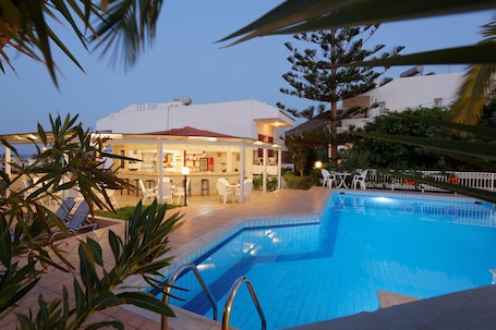 Una piscina al aire libre, sombrillas, sillones reclinables de piscina