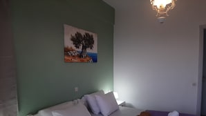 Un dormitorio con cama, almohadas, un sombrero y toallas sobre un edredón morado.