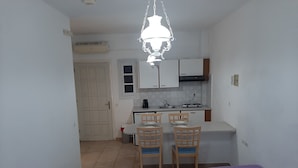 Una habitación pequeña y limpia con dos camas individuales, una kitchenette y un comedor con dos sillas.