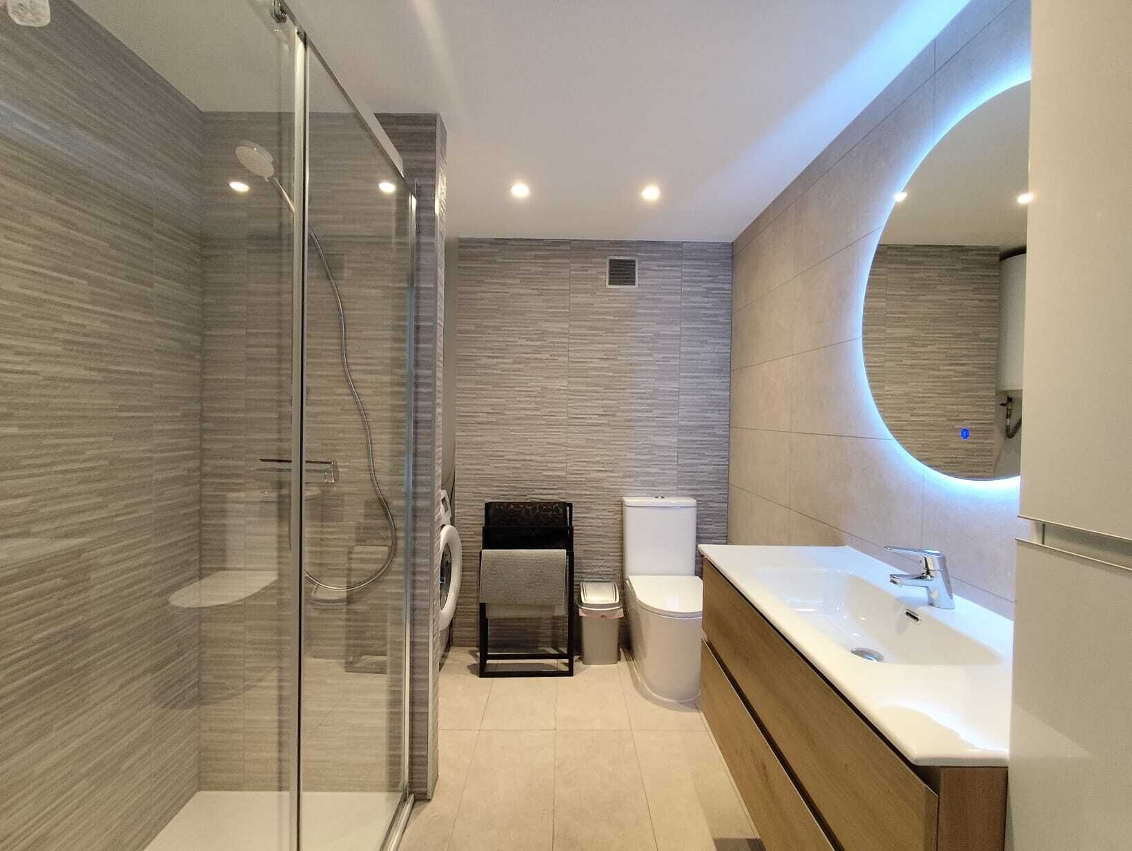 A modern bathroom with a glass shower enclosure, a toilet, and a vanity with a sink.