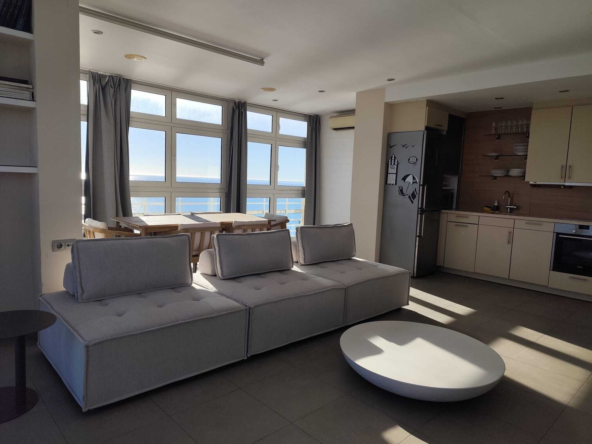 A modern living room with a sofa, a round coffee table, and a dining area with a table and chairs.