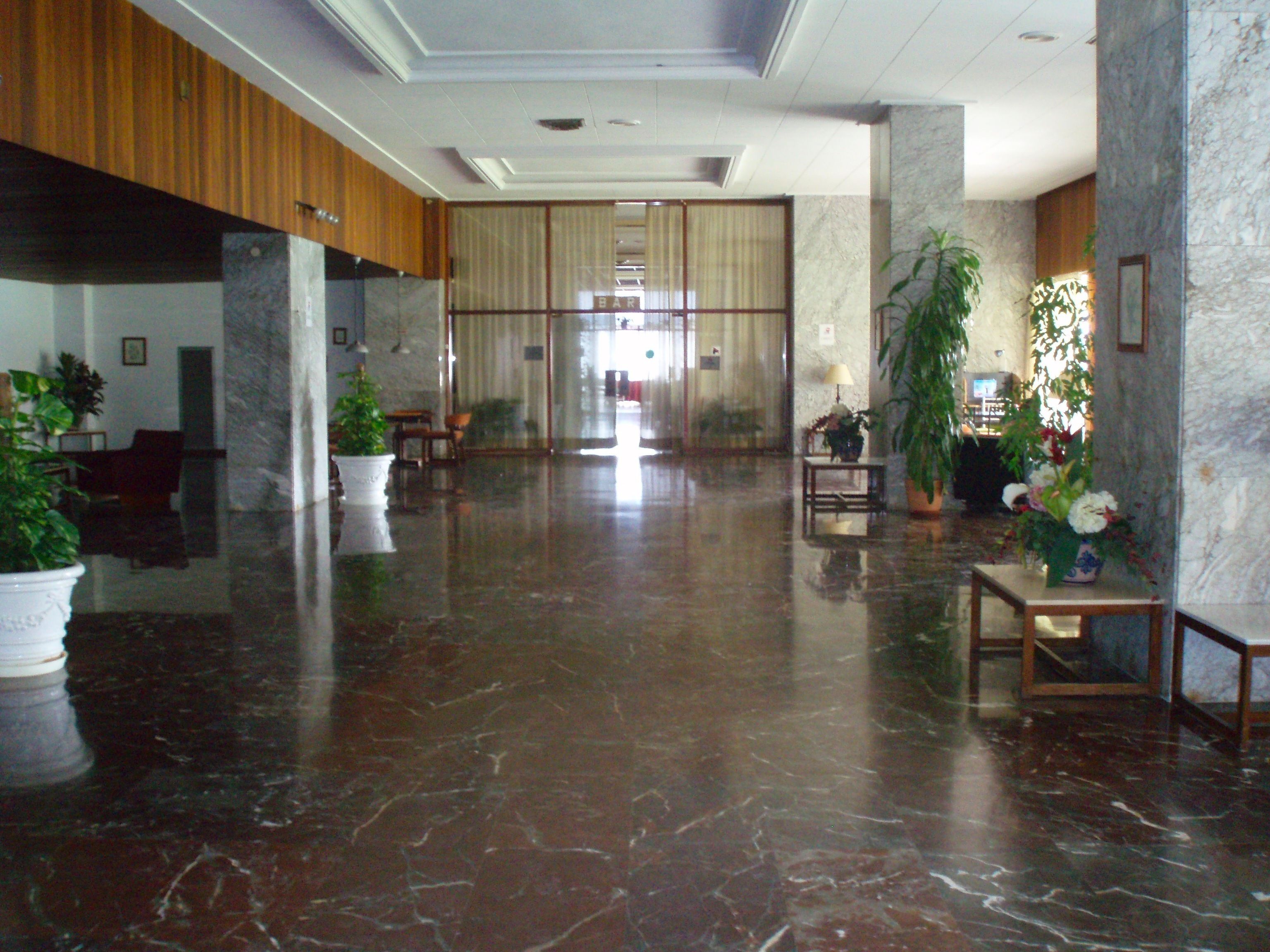 Eine großzügige Lobby mit Marmorböden, Holzvertäfelung und Zimmerpflanzen.