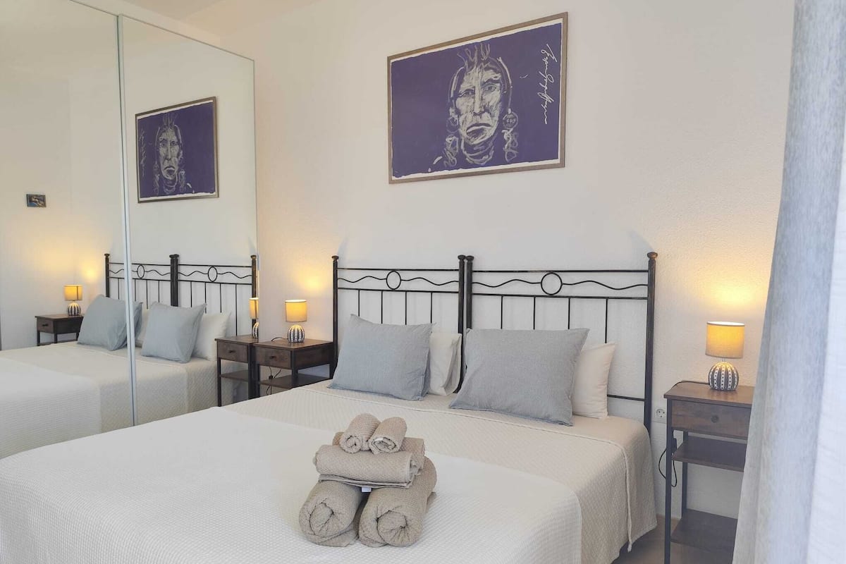 Habitación de hotel con dos camas, un espejo grande y obras de arte en la pared.