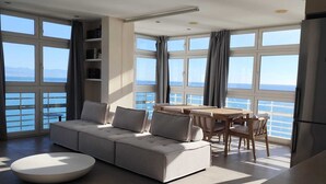 Ein modernes Wohnzimmer mit einer großen Couch, einem Esstisch und Meerblick.