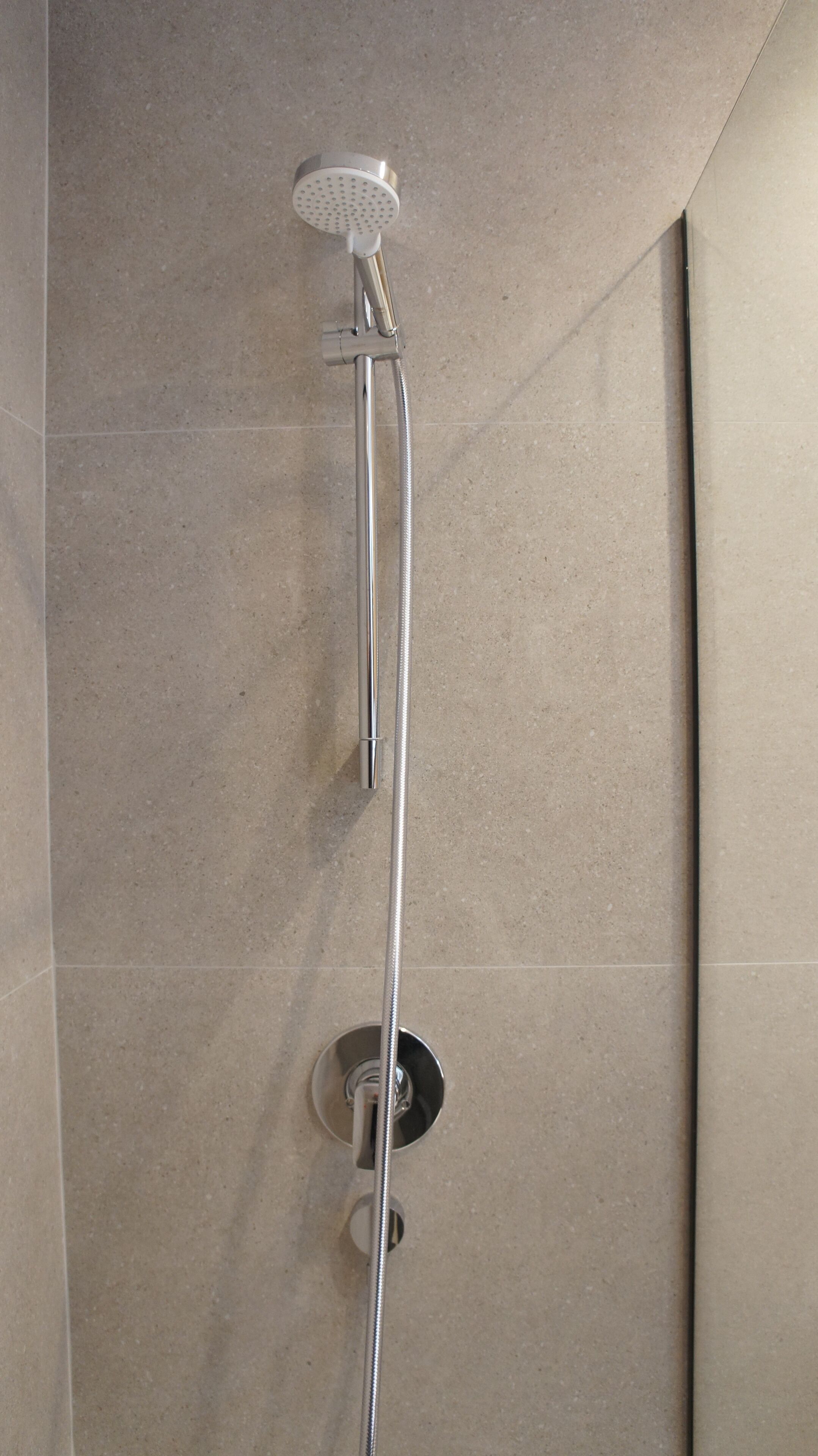 Eine Dusche mit Handbrause und Armaturen an der Wand.
