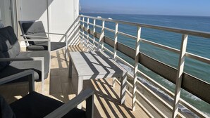 Ein Balkon mit Blick auf das Meer, ausgestattet mit einem Geländer, einem Tisch und zwei Stühlen.