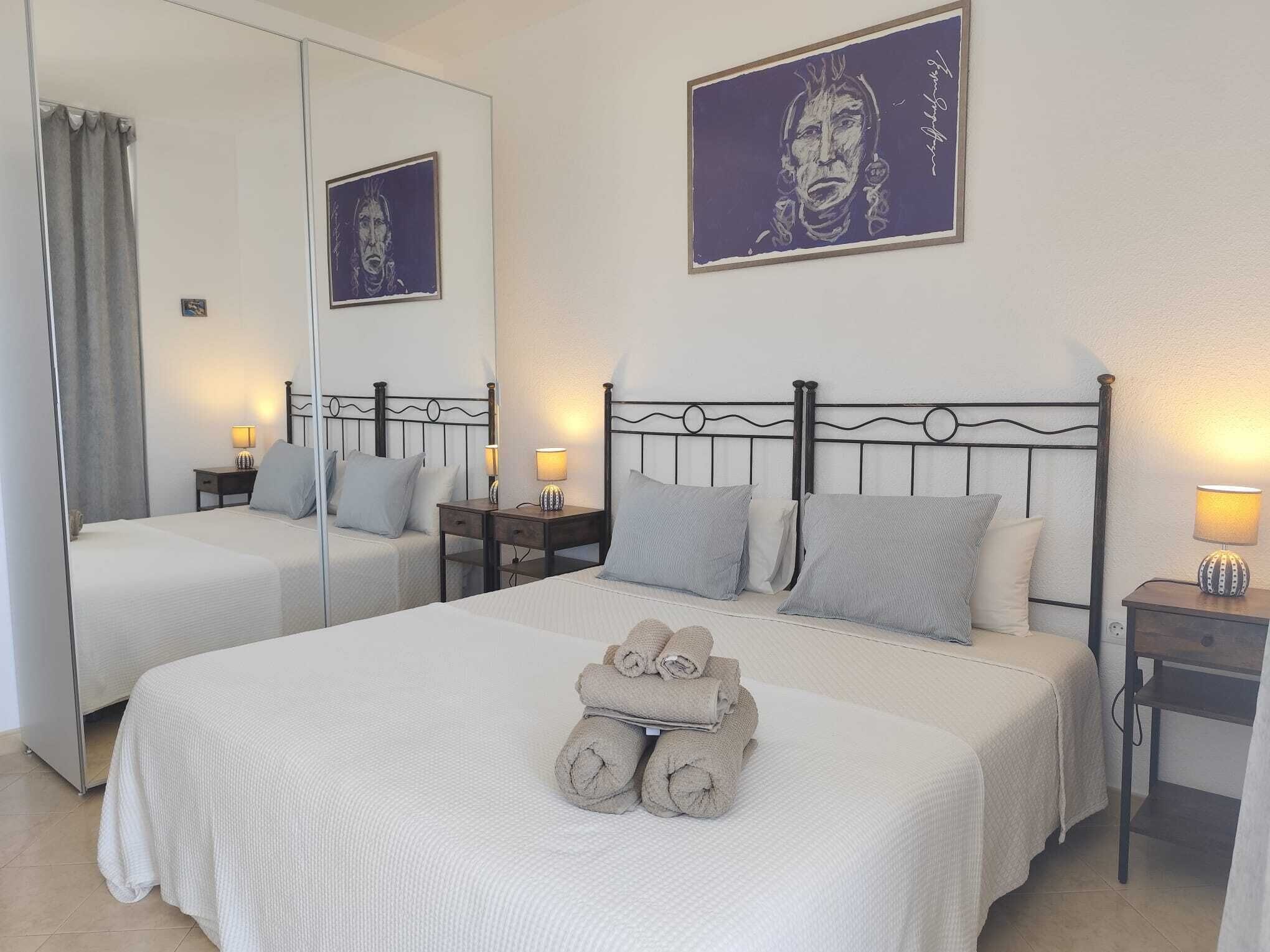 A hotel room with two beds, a large mirror, and artwork on the walls.