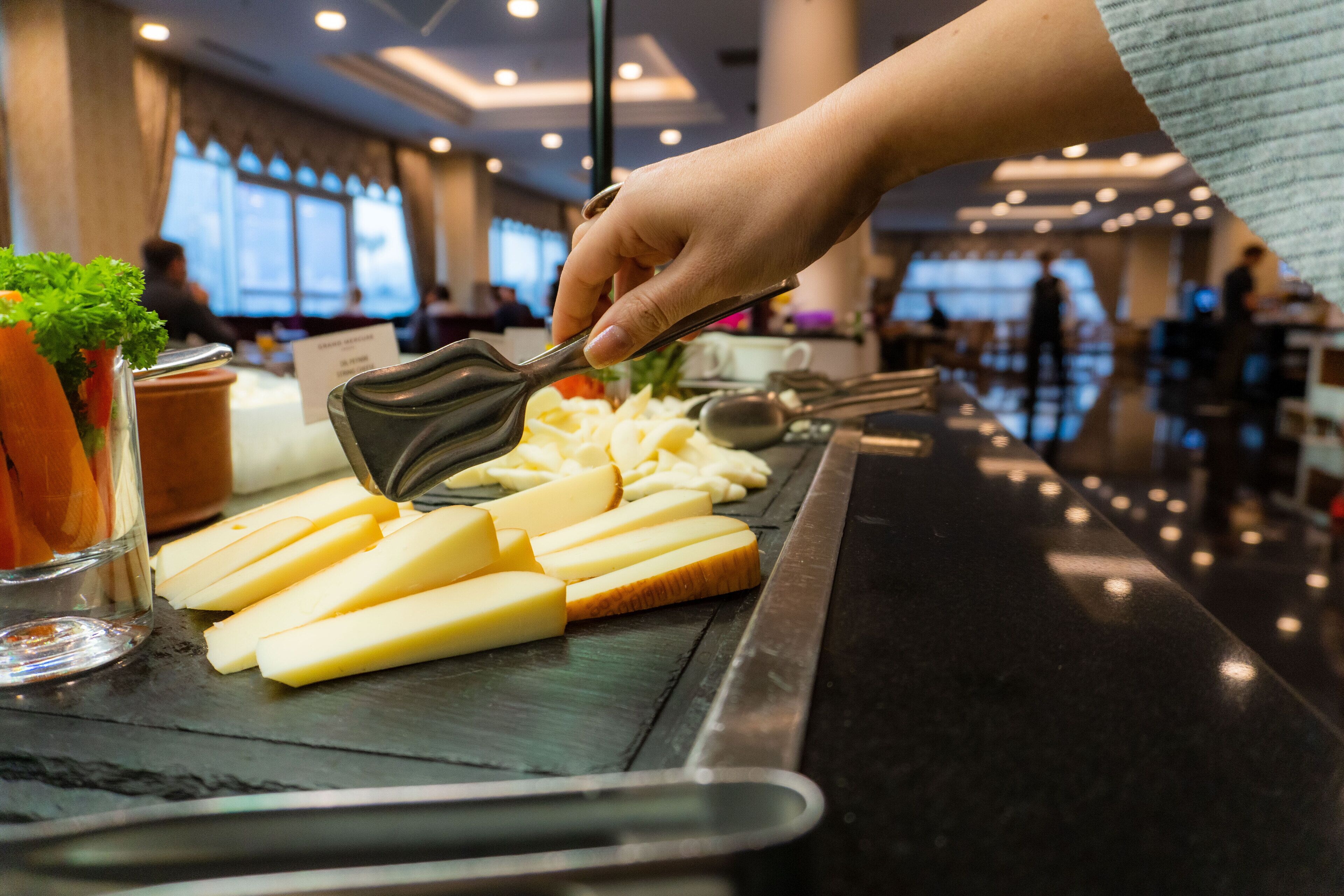 Una persona cortando queso en una mesa de buffet en un hotel.