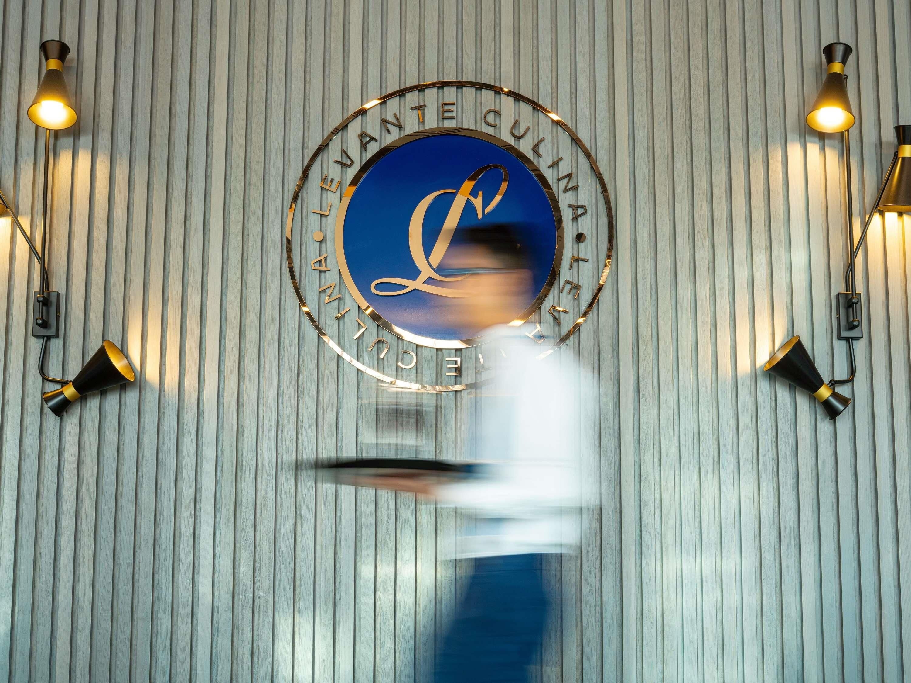 A wall-mounted sign with the text 'LEVANTANTE CUINA' and a logo, surrounded by wall-mounted lights.
