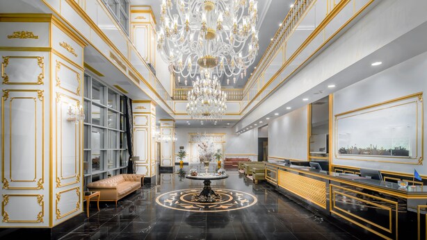 Un hall d’entrée luxueux, agrémenté d’un imposant lustre, de sols en marbre noir et de touches dorées.