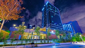 Un hôtel moderne doté d ’une façade en verre remarquable, entouré d’espaces paysagers et offrant une vue sur un ciel nocturne dégagé.