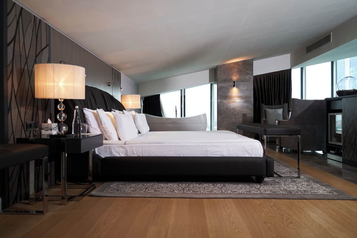 A modern hotel room with a large bed, bedside tables, a desk, and a seating area.