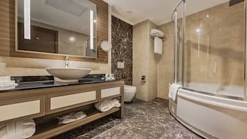 A modern bathroom with a large sink, a mirror, a toilet, and a glass-enclosed shower.