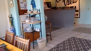 A dining area with a wooden table, chairs, a buffet shelf, and a kitchen counter with a sign reading "Cape View". - Cape View Motel (North Truro)