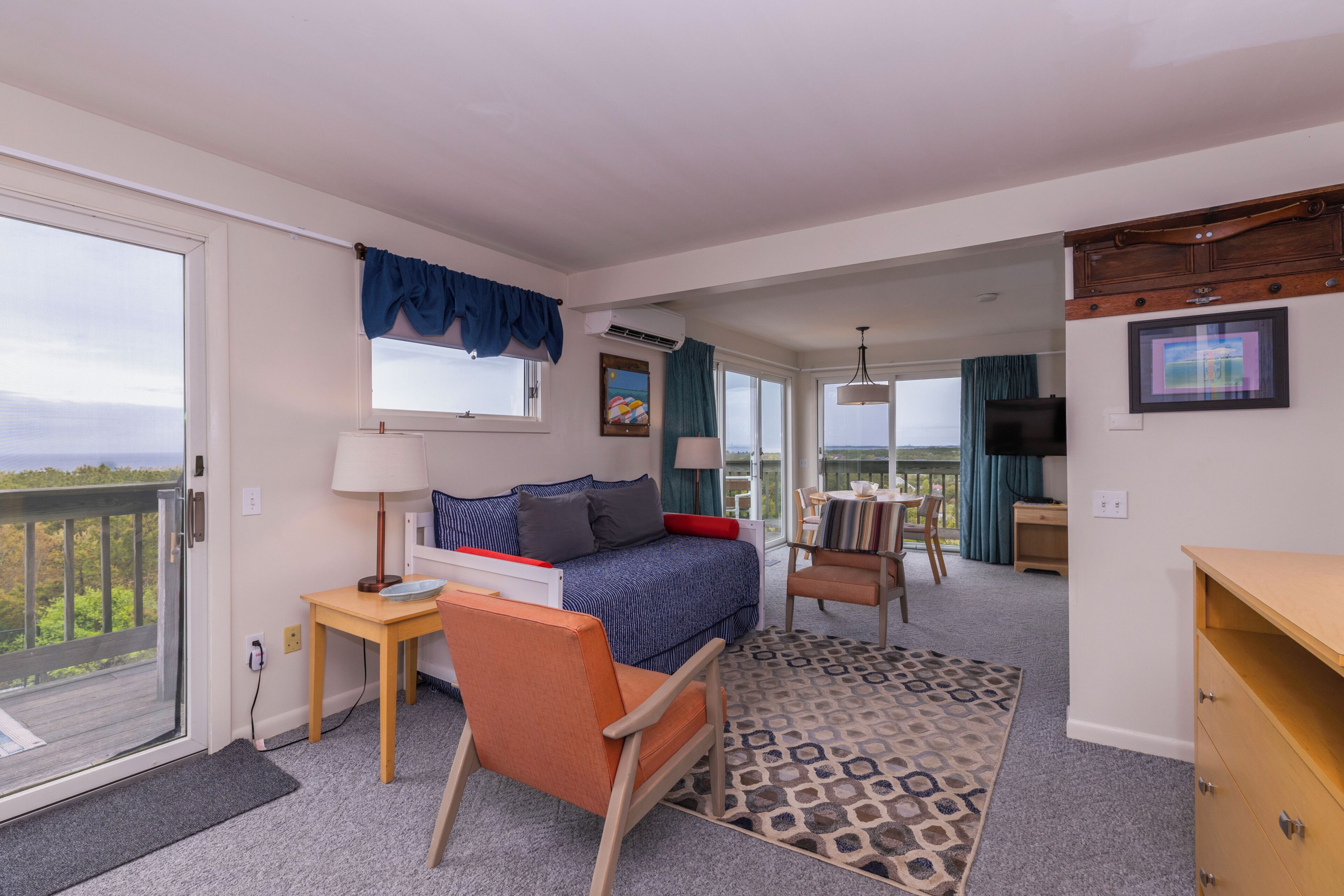A bedroom with a bed, a desk, a chair, a TV, and a balcony.