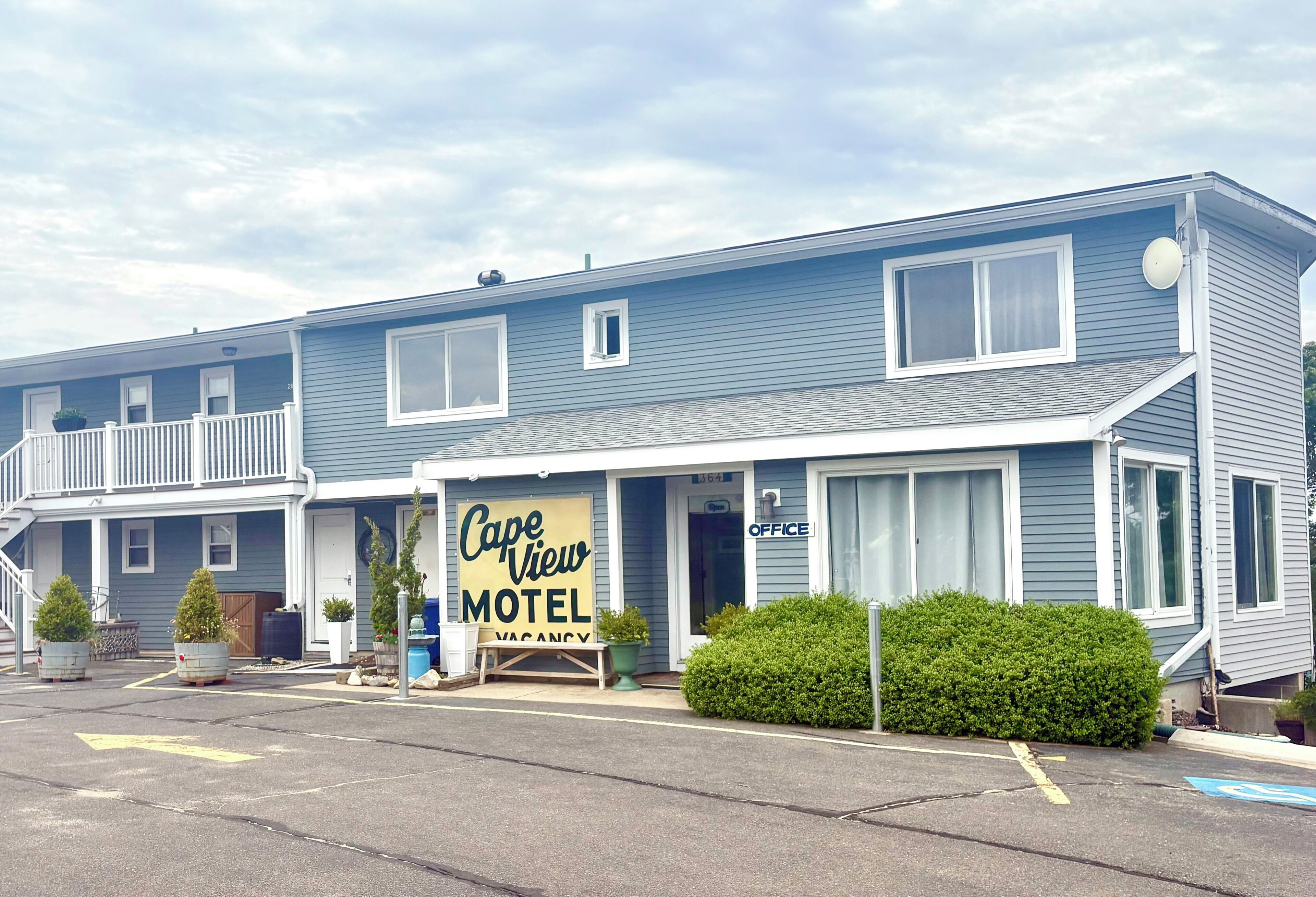 A motel with a signboard, a balcony, and a parking lot.