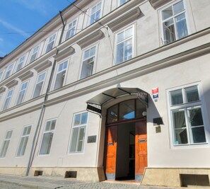 A building with a classic architectural style, featuring a prominent entrance with a wooden door and a sign above it. - Hotel Adler (Prague)