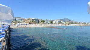 A coastal beach scene with clear water, beach umbrellas, and buildings in the background. - White Gold Hotel & Spa (Alanya)