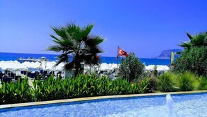 A pool area with a clear view of the sea and a flag in the background. - White Gold Hotel & Spa (Alanya)