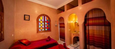 Una habitación con dos camas, un espejo grande y un vitral.