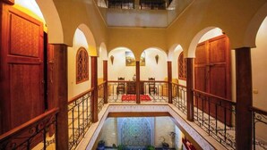 A corridor with arched ceilings, wooden doors, and a central pool area with a patterned floor. - Riad La Lune de Marrakech  (Marrakech)