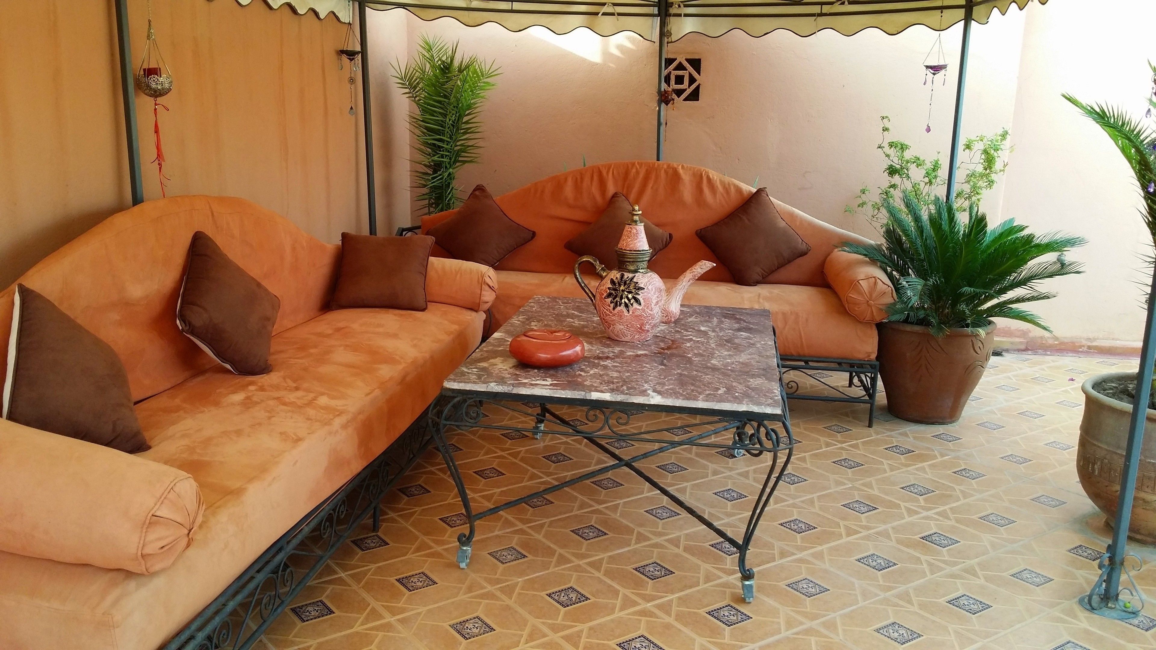 A cozy seating area with a sofa and a table, surrounded by potted plants and decorative items.