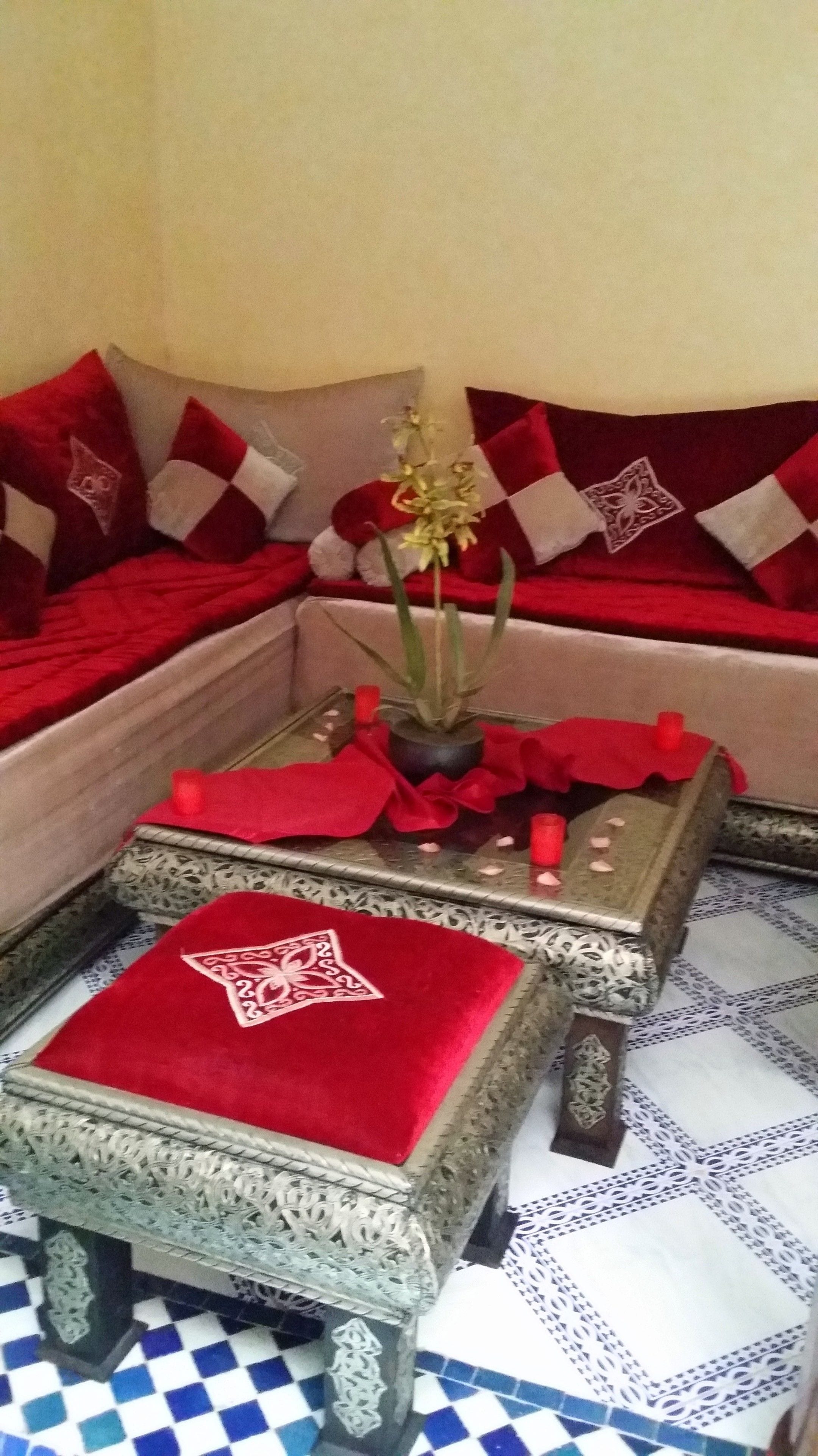 A corner of a room with a sofa, a small table with a red cloth, and a decorative plant.