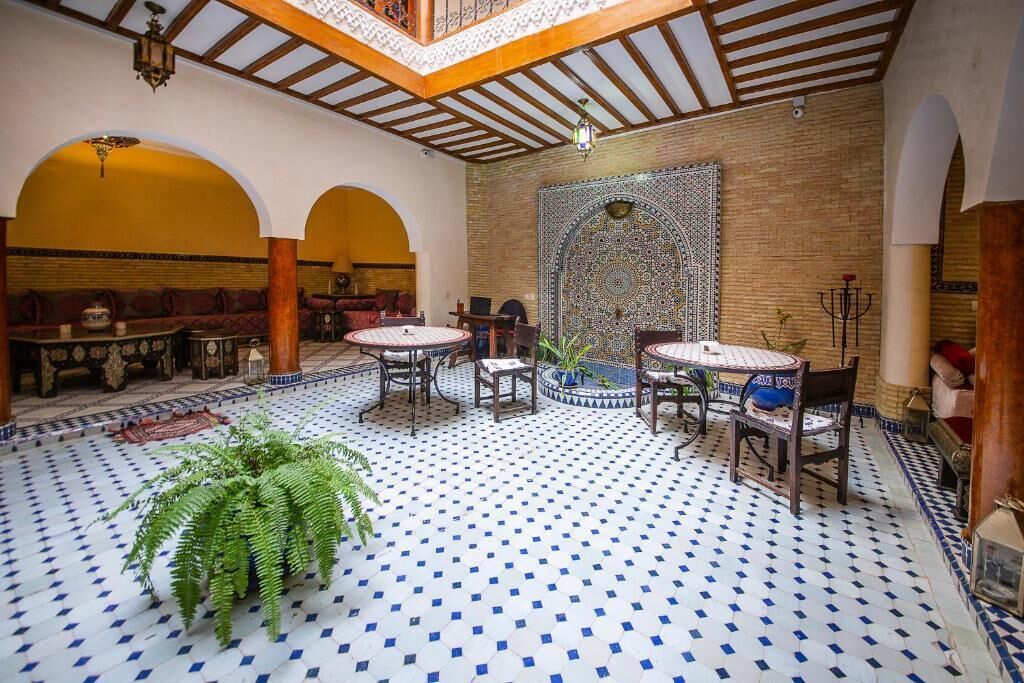 A traditional Moroccan interior with tiled floors, wooden furniture, and a decorative wall.