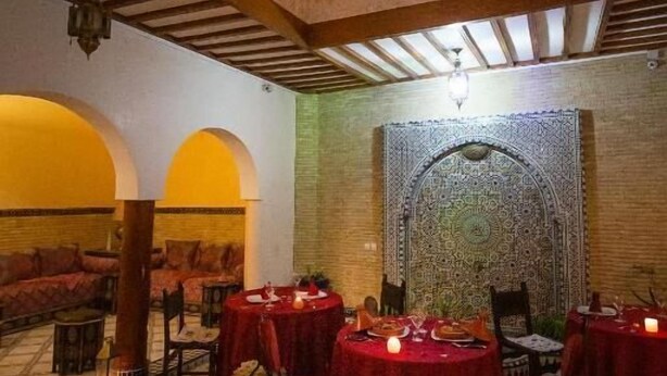 A dining area with round tables covered in red tablecloths, set against a patterned floor and a high ceiling with wooden beams. - Riad La Lune de Marrakech  (Marrakech)