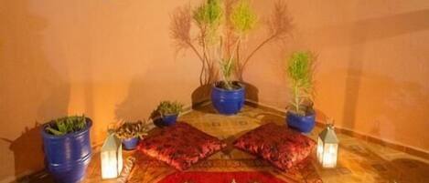 A cozy indoor garden with a patterned rug, potted plants, and decorative lanterns.