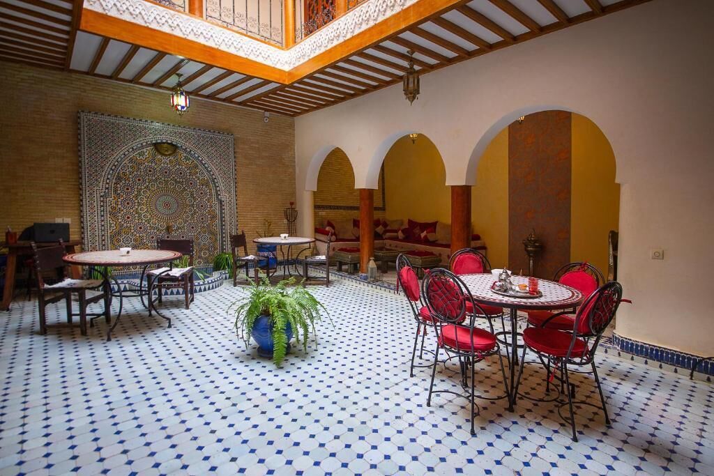 Un intérieur de style marocain, avec un sol carrelé, des meubles rouges et blancs, et des décorations murales élaborées.