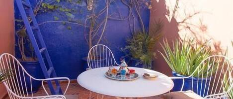 A small outdoor patio with a round table and four white metal chairs.