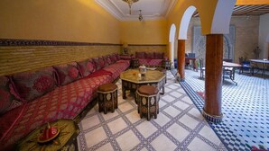 A Moroccan-style interior with a long sofa, a round table, and patterned floor tiles. - Riad La Lune de Marrakech  (Marrakech)