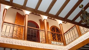 A balcony with wooden railings and decorative ironwork, a wooden ceiling, and a view of the interior. - Riad La Lune de Marrakech  (Marrakech)
