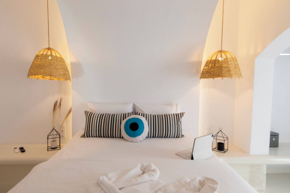 Un dormitorio moderno con una cama grande, dos lámparas colgantes y un diseño de techo único.