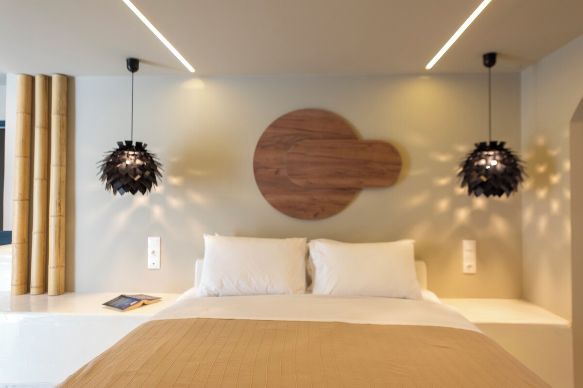 Quarto moderno com uma cama grande, duas luminárias pendentes e uma obra de arte de madeira na parede.