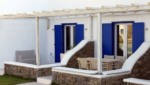 Un espacio al aire libre cubierto con paredes de piedra y contraventanas azules, que incluye una mesa y sillas.