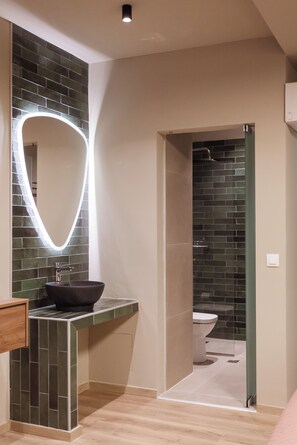 Casa de banho com lavatório preto, espelho com luz e zona de duche.