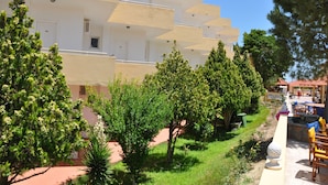 Un edificio de varios pisos con balcones, rodeado de vegetación y zonas de estar al aire libre.